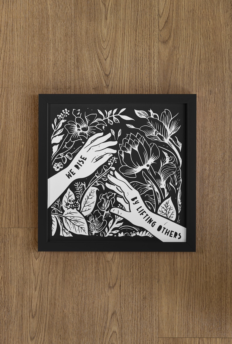 May include: Black and white framed print with a floral design and two hands reaching up. The text "We rise by lifting others" is written on the hands.
