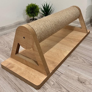 May include: A wooden cat scratching post with a sisal rope covered cylinder. The post is shaped like a triangle with a flat base.