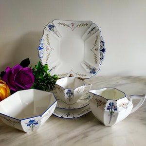 Può includere: Un set da tè vintage con un motivo floreale blu e bianco. Il set comprende una teiera, una zuccheriera, un creamer e un piatto da torta quadrato.