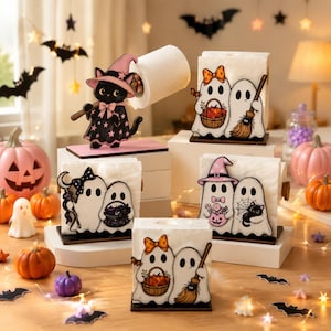 May include: A collection of wooden Halloween-themed holders for toilet paper and napkins. The items feature illustrations of black cats in pink hats and white ghosts with pumpkins, brooms, and bows, all mounted on rectangular wooden bases.