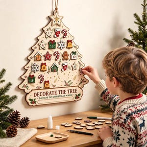 May include: A wooden Christmas tree-shaped advent calendar with the text DECORATE THE TREE 24 DAYS OF CHRISTMAS MAGIC. It features numbered slots for small ornaments including stars, bells, gifts, and candy canes, with a hanging rope at the top.