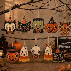Pode incluir: Uma coleção de dez enfeites de Halloween pendurados com ilustrações de um morcego, gato preto, monstro de Frankenstein, abóbora, coruja, lanterna, fantasma, caveira, fantasma de doce e outro gato preto, todos suspensos por barbante.