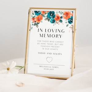 May include: A white sign with black text in a gold frame. The sign says "In Loving Memory" and has a floral design with teal and orange flowers. The text continues, "For those who cannot be here today, but are forever present in our hearts. Today and always." The sign is signed "Melissa & James 18.08.2025".