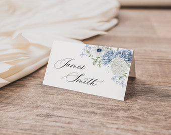 May include: A white place card with blue and white floral design. The name "James Smith" is written in cursive on the card.