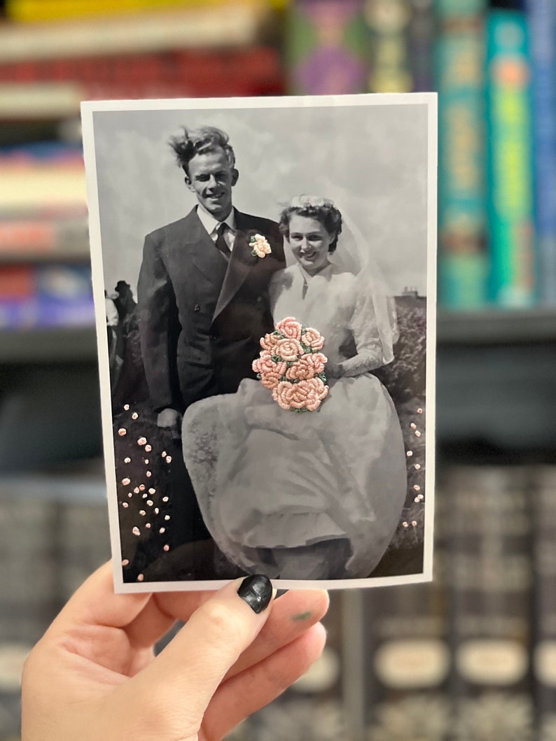 K&ouml;nnte beinhalten: Ein Schwarzwei&szlig;-Hochzeitsfoto eines Paares. Die Braut tr&auml;gt ein wei&szlig;es Kleid und h&auml;lt einen Strau&szlig; rosa Blumen. Der Br&auml;utigam tr&auml;gt einen Anzug und eine Krawatte. Das Foto ist in einem wei&szlig;en Rahmen.