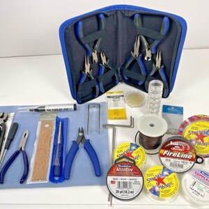 May include: A jewelry-making kit with various tools and supplies. Includes pliers, wire, needles, and spools of thread. The kit also contains a blue zippered case, a blue mat, and several containers of beads and findings.