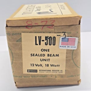 May include: A rectangular cardboard box with the text "LV-500 ONE SEALED BEAM UNIT 12 Volt, 18 Watt." The box has a sticker with the American flag and "MADE IN U.S.A." The box is brown with some text and markings.