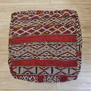 Peut inclure: Un coussin de sol carré avec un motif géométrique rouge, noir, blanc et bleu.