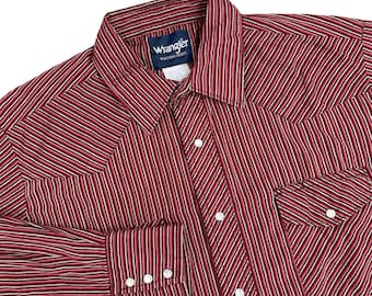 Może przedstawiać: Czerwono-biała koszula Western Wrangler w paski. Koszula ma przód zapinany na guziki, dwie kieszenie na piersi i mankiety zapinane na guziki. Etykieta Wrangler jest widoczna na kołnierzu.