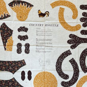 Op de afbeelding: Een stoffen paneel met uitgesneden vormen voor een "Country Rooster" project. Het paneel bevat illustraties van hanen, bloempatronen in bruin en geel en instructies. De tekst "COUNTRY ROOSTER" is op de stof gedrukt.