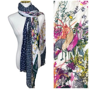 May include: A long scarf featuring a patchwork design with multiple patterns. One section has a dark blue background with white fan-shaped motifs, while another displays a cream background with colorful illustrations of cranes and floral patterns.