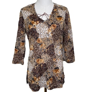 May include: A long-sleeve top with a V-neck and a floral patchwork design. The top features a brown lace-up detail at the neckline and three-quarter sleeves. The color palette includes shades of brown, beige, and white.