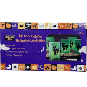May include: A rectangular product box for a set of 5 outdoor Halloween luminaries by Halloween Alley. The purple box features a graphic of green paper bags with haunted house cutouts, 14 ft. string length, and five 7 watt bulbs.