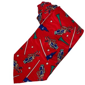 May include: A red necktie featuring a repeating pattern of golf equipment, including blue and white golf bags filled with clubs, green golf tees, white golf balls, and blue golf flags marked with the numbers two, six, and nine on a red background.