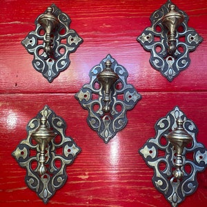 May include: Five ornate metal hooks with a diamond shape and intricate scrollwork design. Each hook has a decorative finial in the center.