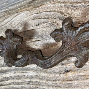 Könnte beinhalten: Ein Schubladenzug aus Gusseisen mit einem dekorativen floralen Design. Der Zug ist dunkelbraun und hat einen leicht gealterten Look.