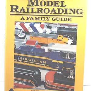 May include: A yellow book cover with the title "Model Railroading: A Family Guide" and a photo of a variety of model trains. The author is Bruce Greenberg.