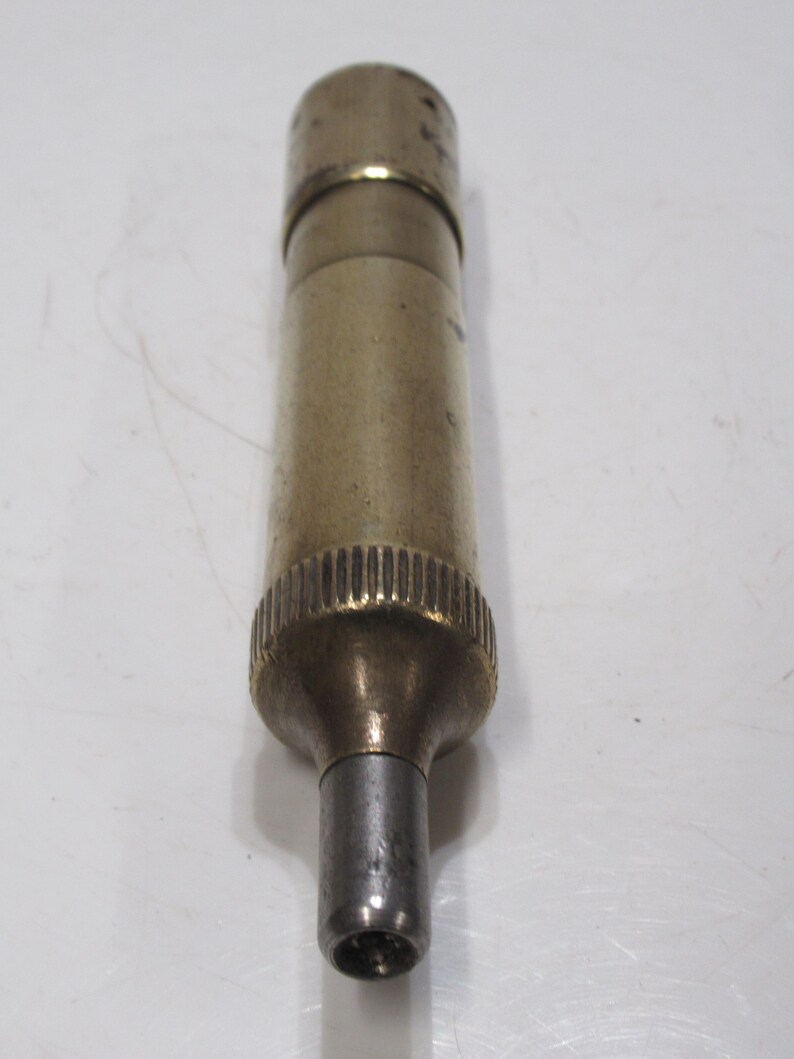 May include: A vintage brass and silver-toned metal object with a cylindrical body. The object has a textured grip and a small, hollow tip. The brass has a slightly aged appearance.