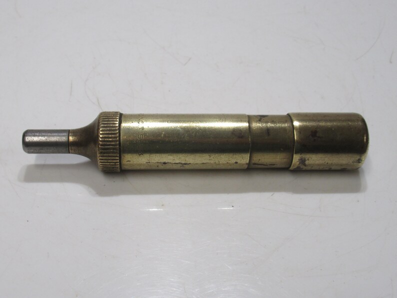 May include: A vintage brass telescope with a silver eyepiece. The cylindrical telescope has a ribbed section near the eyepiece and a smooth, rounded end. The brass has a slightly aged patina, showing its age.