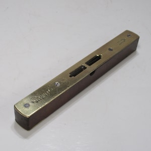 Puede incluir: Un nivel antiguo con un cuerpo de madera oscura y una parte superior de latón. La parte superior de latón tiene dos ventanas de visualización y está asegurada con tornillos pequeños. El nivel tiene el texto "Stanley" y "Made in USA" grabado.