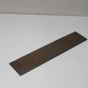 May include: A rectangular, brown metal plate. The plate is long and narrow, with a slightly textured surface. The item is set against a white background.