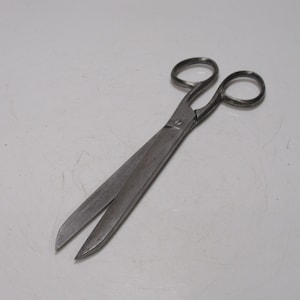 May include: A pair of vintage metal scissors with large finger loops and long, pointed blades. The scissors are silver-toned and appear to be well-used, with some wear visible on the metal. The blades are open, suggesting they are ready for use.