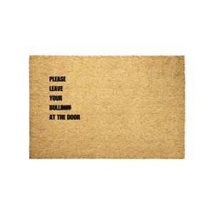 May include: A brown coir doormat with the text "PLEASE LEAVE YOUR BULLSH*T AT THE DOOR" printed in black.