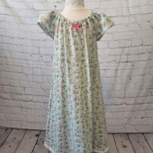 May include: A light green floral print nightgown with short sleeves and a lace trim. The gown has a pink bow at the neckline.