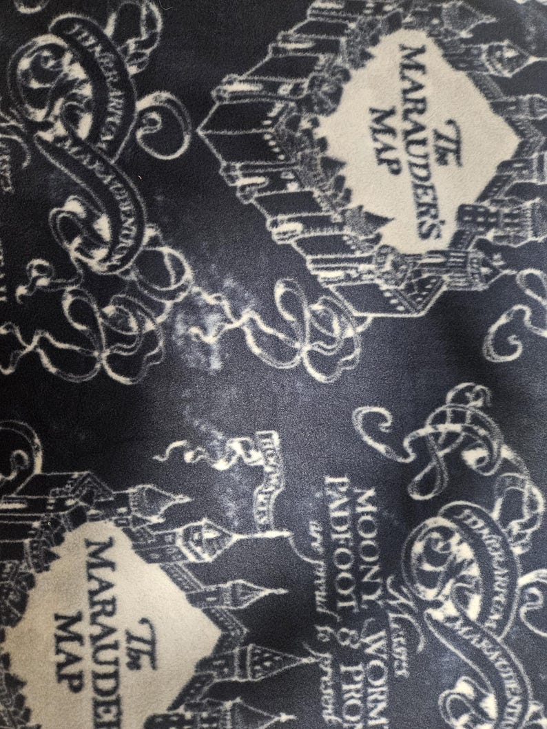 Puede incluir: Tela azul marino con un dise&ntilde;o de mapa ilustrado en blanco. El texto "The Marauder's Map" es visible, junto con otros textos e ilustraciones de edificios y pergaminos. El dise&ntilde;o es un patr&oacute;n repetitivo.