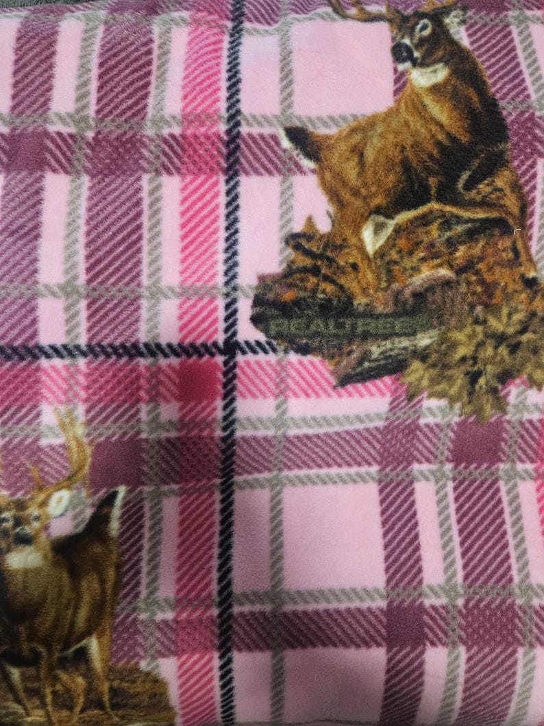 Puede incluir: Manta de forro polar a cuadros rosas con ilustraciones de ciervos. La manta tiene un dise&ntilde;o a cuadros rosa, burdeos y gris. Los ciervos est&aacute;n impresos en la manta en tonos marrones y beige. La manta es suave y acogedora.