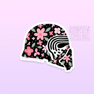 Peut inclure: Un autocollant représentant un casque noir orné de fleurs roses et de feuilles vertes. Le casque a un contour blanc et une section avec des rayures noires et blanches. Le texte "KIMBERLY STERLING ARTS" est visible.