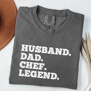 May include: A gray t-shirt with the text "Husband. Dad. Chef. Legend." printed in white.