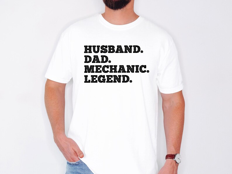 Puede incluir: Camiseta blanca con texto negro que dice "Husband. Dad. Mechanic. Legend."