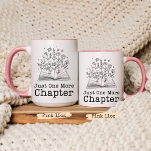 Puede incluir: Dos tazas de cer&aacute;mica blanca con bordes rosados. Ambas tazas presentan una ilustraci&oacute;n en blanco y negro de un libro abierto con flores que crecen de &eacute;l. El texto "Just One More Chapter" est&aacute; impreso en ambas tazas. La taza m&aacute;s grande est&aacute; etiquetada como "Pink 15oz" y la taza m&aacute;s peque&ntilde;a est&aacute; etiquetada como "Pink 11oz".