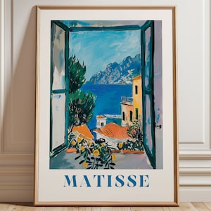 Könnte beinhalten: Ein gerahmter Druck eines Gemäldes von Henri Matisse, das einen Blick aus einem Fenster zeigt. Das Gemälde zeigt eine farbenfrohe Szene einer Küstenstadt mit Gebäuden, einem blauen Meer und grünen Bäumen. Der Text "MATISSE" ist unter dem Bild gedruckt.