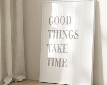 May include: White framed print with the text "GOOD THINGS TAKE TIME" in a light brown color. The print is hanging on a white wall next to a beige curtain.