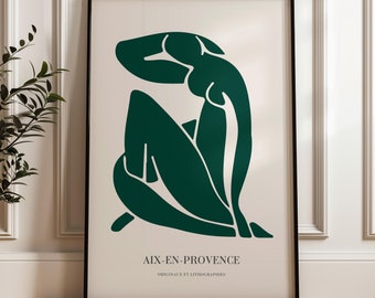 May include: A framed art print featuring a minimalist illustration of a seated figure in a dark green hue against a cream background. The artwork is enclosed in a black frame, with text at the bottom reading "AIX-EN-PROVENCE".
