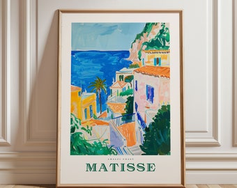 May include: A framed art print featuring a colorful coastal scene in the style of Matisse. The artwork depicts buildings with orange roofs, a blue sea, and a palm tree. The text "MATISSE" is printed at the bottom.