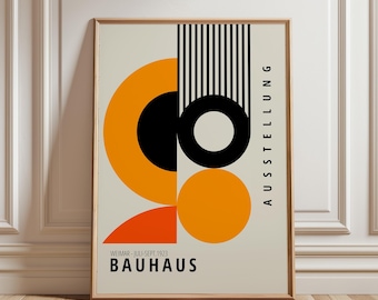 May include: A rectangular poster in a light beige frame featuring a geometric Bauhaus design. The artwork displays black and orange circles, semicircles, and vertical lines. The text reads AUSSTELLUNG, WEIMAR - JULI-SEPT. 1923, and BAUHAUS.