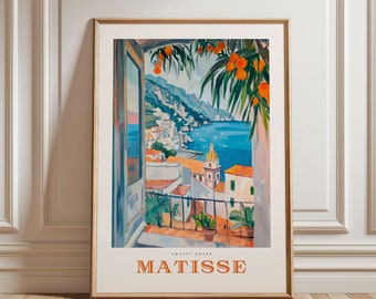 May include: Framed art print featuring a coastal scene with a view from a balcony. The artwork depicts a blue sea, white buildings, and orange trees. The text "MATISSE" is printed in orange at the bottom of the print.