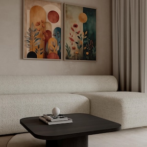 Puede incluir: Dos impresiones art&iacute;sticas enmarcadas con dise&ntilde;os florales y geom&eacute;tricos abstractos. Las impresiones presentan tonos c&aacute;lidos de naranja, rojo y amarillo, con toques de azul y verde. La obra de arte se exhibe sobre un sof&aacute; blanco y una mesa de centro de madera oscura.