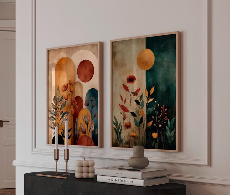 Puede incluir: Dos impresiones art&iacute;sticas abstractas enmarcadas. Una presenta formas de arco en naranja, marr&oacute;n y verde azulado con detalles florales. La otra tiene un fondo dividido en beige y verde azulado con un sol amarillo y flores rojas. Los marcos son de madera clara.