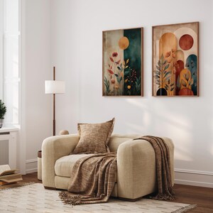 Puede incluir: Un sal&oacute;n acogedor con un sill&oacute;n beige, una manta y un coj&iacute;n a juego. Dos obras de arte abstractas enmarcadas, con motivos bot&aacute;nicos y tonos tierra, adornan la pared. Una l&aacute;mpara de pie y una ventana completan el ambiente.