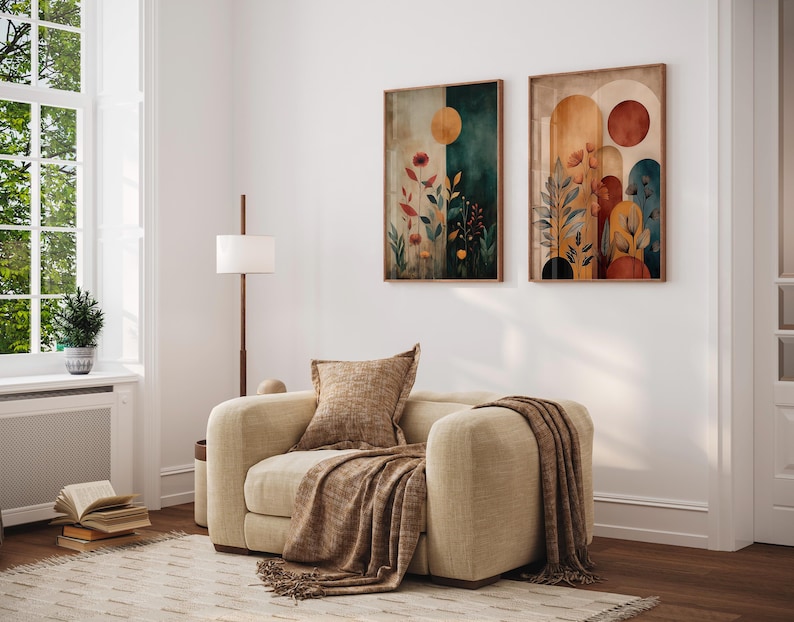 Puede incluir: Un sal&oacute;n acogedor con un sill&oacute;n beige, una manta y un coj&iacute;n a juego. Dos obras de arte abstractas enmarcadas, con motivos bot&aacute;nicos y tonos tierra, adornan la pared. Una l&aacute;mpara de pie y una ventana completan el ambiente.