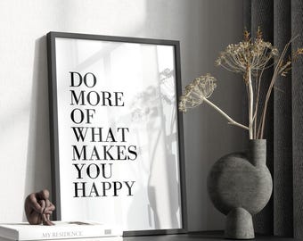 May include: Black and white framed print with the text "Do more of what makes you happy". The print is on a white background and is sitting on a black shelf with a book and a decorative vase.