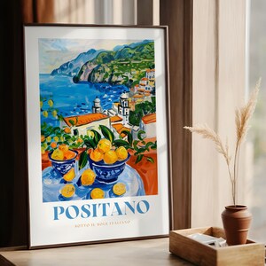 May include: A colorful painting of a coastal town with a bowl of lemons in the foreground. The painting is titled "Positano" with the text "Sotto il sole italiano" below.