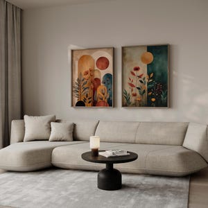 Puede incluir: Dos impresiones art&iacute;sticas enmarcadas con temas bot&aacute;nicos cuelgan sobre un sof&aacute; seccional beige. La obra de arte presenta tonos c&aacute;lidos de naranja, rojo y amarillo, con motivos florales y de hojas. Una peque&ntilde;a mesa negra con una l&aacute;mpara y libros est&aacute; frente al sof&aacute;.