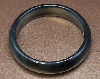 May include: A black jade bangle bracelet. The bracelet is smooth and polished.