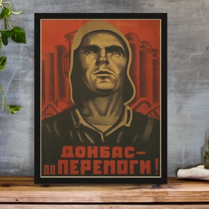Könnte beinhalten: Ein Vintage-Sowjet-Propagandaplakat mit rotem Hintergrund und einem Mann in einer Kapuzenjacke. Das Plakat zeigt den Text "Donbas - Zum Sieg!" in kyrillischer Schrift.