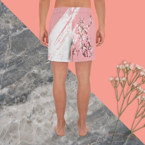 May include: Pink and white patterned men's athletic shorts with a white brushstroke design and pink cherry blossoms.